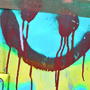 Ein Graffiti auf einem Transformatorenhäuschen: Ein Smilie, dessen Farbe verläuft und Freude und Leid vereint.